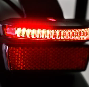 Close-up of a bright red LED bicycle tail light with a honeycomb reflector for night safety.