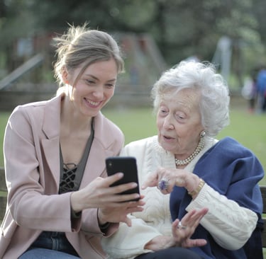 Young woman and elderly woman using smartphone together on a bench