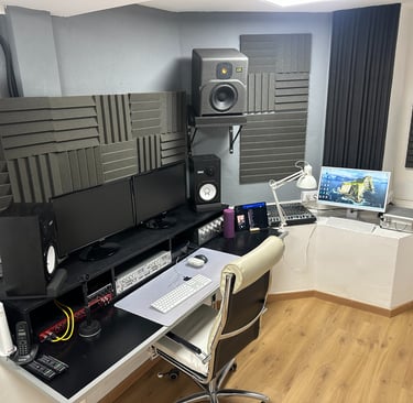 recording music studio with a computer monitor, speakers, and a laptop