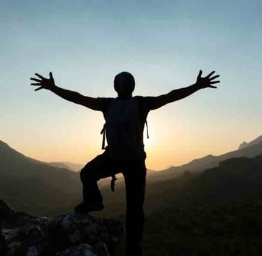 silhouette of person on top of a mountain arms outstretched