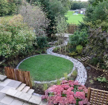 A Landscape Design in Bury, Manchester showing a round lawn and sinuous path from reclaimed setts