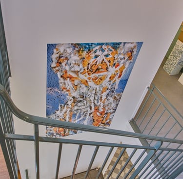 A colorful portrait painting on a wall viewed from a modern staircase with metal railings.