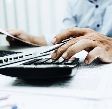 Plumber typing on calculator while working on JobberBooks bookkeeping.