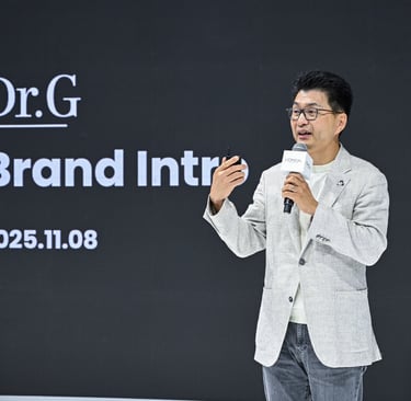 A man in a blazer gives a Dr.G skincare brand introduction presentation at a L'Oreal event.