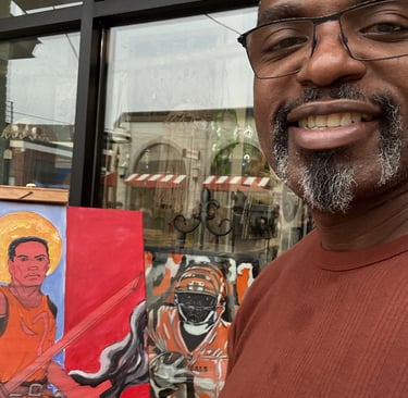 A smiling artist stands next to his vibrant canvas paintings in progress.