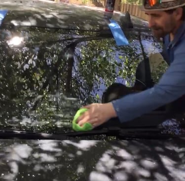 A Technician is finishing a windshield replacement and wiping down the windshield.