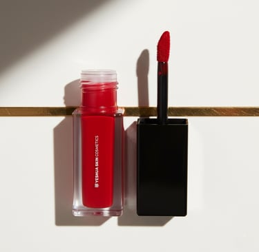 YESHUA Skin Cosmetics vibrant red lip stain bottle with an open applicator brush on a white surface.