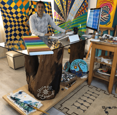 Artist Yous sitting with many oil paintings around