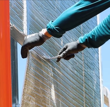 Person installing insulation on metal building
