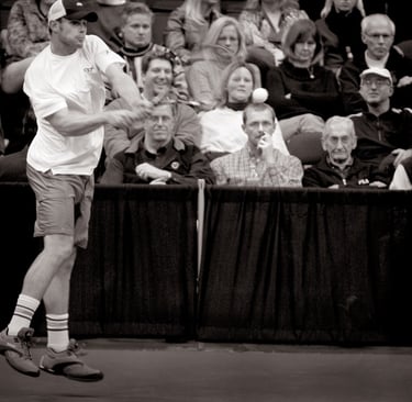 a man playing tennis in a crowd of people