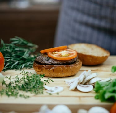 chef making a delicious burger with beef, tomato, mushrooms and onions.