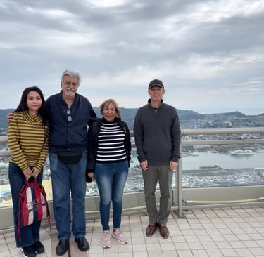 Two local guides and a couple taking a commemorative photo at the Mt. Inasa observation deck in Naga