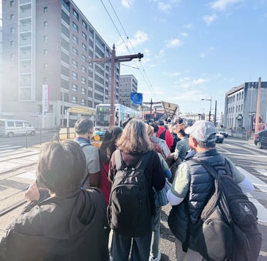 Crowded tram stop in Nagasaki with many tourists waiting to board during peak travel time