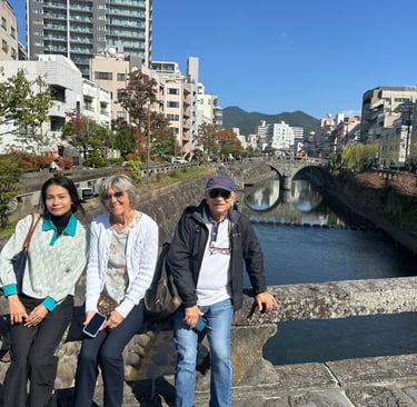 A guide and a couple with Meganebashi Bridge in the background in Nagasaki