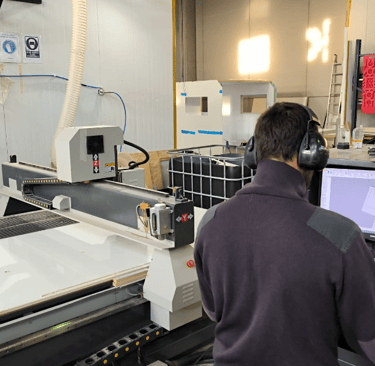 a man in a factory with a machine that is cutting into a sheet