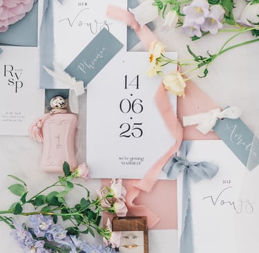 Wedding flat lay photo with stationery, blue ribbon, and pastel coloured flowers