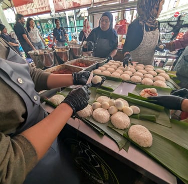 Street food vendors preparing traditional Nasi Lemak on banana leaves with rice and boiled eggs.