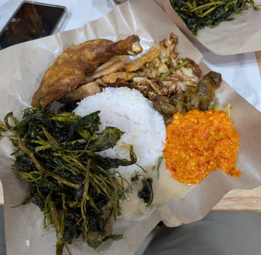 Ma Nasi Ayam Goreng with fried chicken, white rice, spicy sambal, and sautéed greens on brown paper.