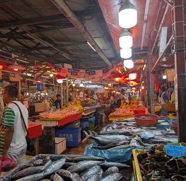 Fresh fish and seafood on display at a bustling Malaysian wet market with local vendors.