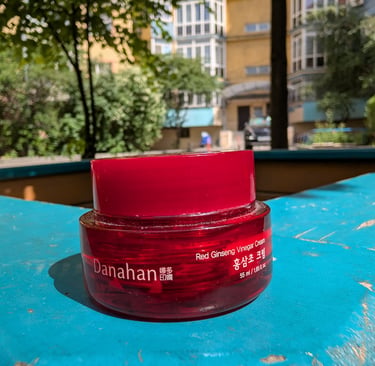Danahan Red Ginseng Vinegar Cream in a red glass jar on a blue ledge with sunlight.