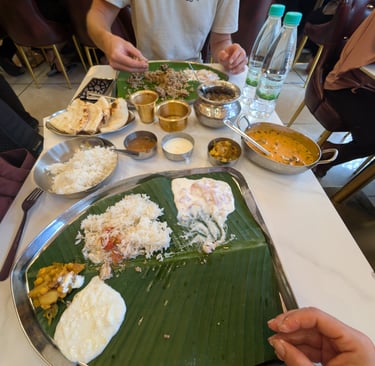 Traditional South Indian thali meal served on a banana leaf with rice, curry, and raita at Erode Amm