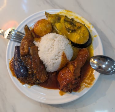 Nasi Lemak plate with steamed white rice, spicy sambal chicken, eggplant, and fish curry.