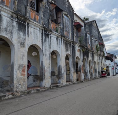 Historic colonial buildings with arched walkways on a street in George Town, Penang.