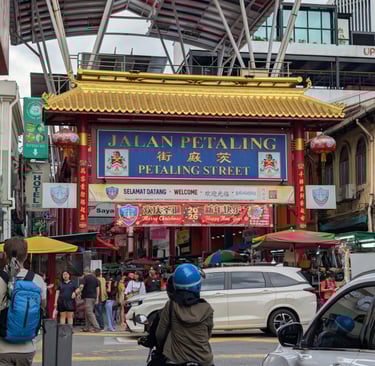 The iconic Petaling Street gate entrance to Kuala Lumpur Chinatown with busy street market and shoppers.