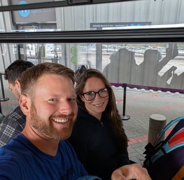 Moose and Bugs taking a selfie while waiting inside an airport shuttle bus at Gate H.