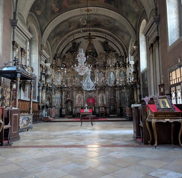 The interior of the Church of Almashka with ornate wood framed wall frescos and a painted ceiling.