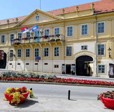 A yellow European style building near an intersection with flowers in Sremski Karlovci, Serbia
