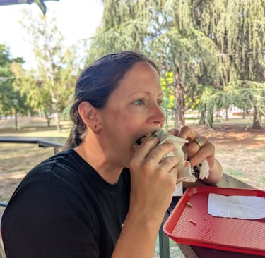 Bugs eating a burger on an outdoor patio with trees in the background.