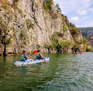 people kayaking in Matka Canyon with beautiful clif walls, North Macedonia 