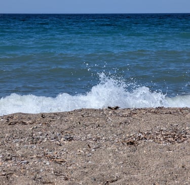 waves crashing on the sandy beach of Paralia Petra in Petra, Greece