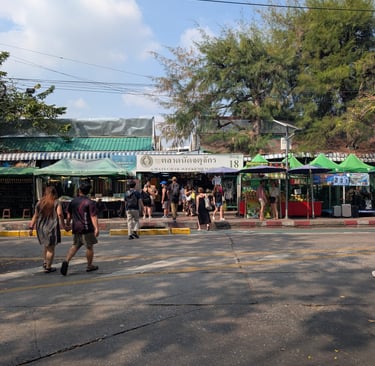 Tourists walking toward the entrance of Chatuchak Weekend Market in Bangkok, Thailand.