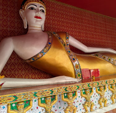 Reclining golden Buddha statue with red and gold wall in a Buddhist temple, Thailand.