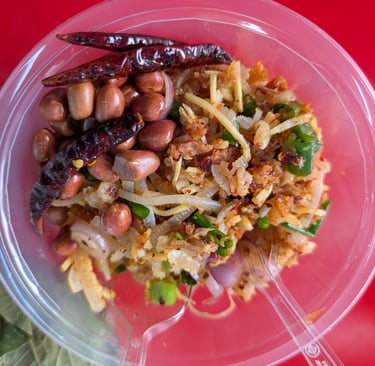 Thai fermented pork salad with peanuts and dried chilies in a plastic bowl Talat Phlu Market.
