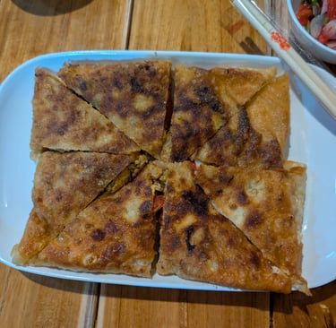 Crispy golden-brown chicken keema prata served on a white plate with dipping sauce and chopsticks.