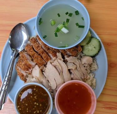 Thai Hainanese chicken rice plate with crispy fried chicken, steamed chicken, broth, and dipping sauces.