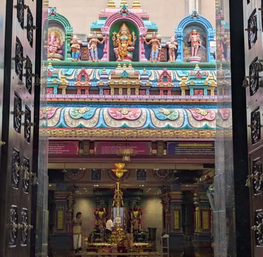 View through open temple doors of colorful Hindu deities and the interior of Sri Mariamman Temple.