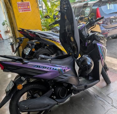 A purple Yamaha Ego Avantiz scooter with its seat open parked on a street in Malaysia.