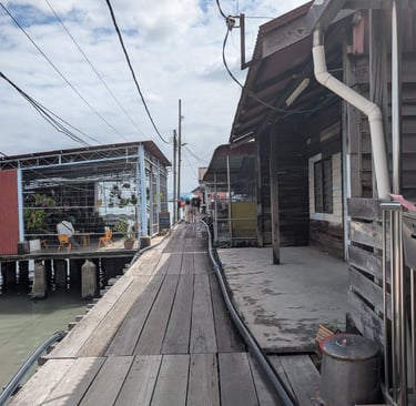 Rustic wooden walkway between stilt houses at Tan Jetty in Penang, Malaysia.