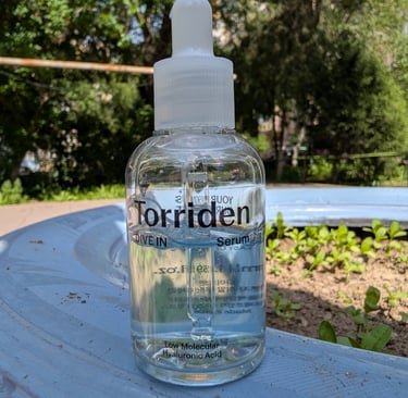 Torriden Dive In Low Molecular Hyaluronic Acid Serum in a clear bottle outdoors.