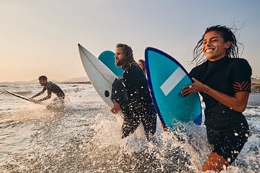 a mixed group surfing at sunset