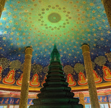Intricate emerald glass stupa inside Wat Paknam Phasi Charoen temple with a celestial painted ceiling.