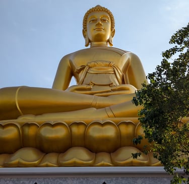 A giant golden Buddha statue sitting in a meditative pose at a Buddhist temple in Thailand.