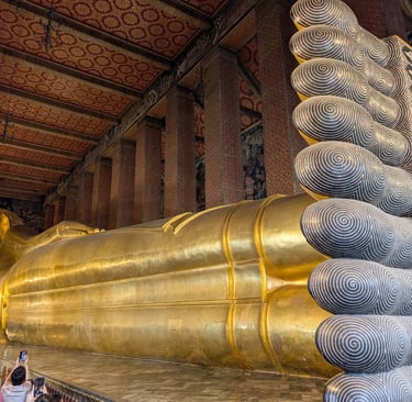 The giant gold Reclining Buddha statue at Wat Pho temple in Bangkok showing intricate mother-of-pearl feet.