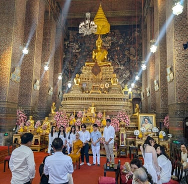 Visitors posing with a monk inside Wat Phra Chetuphon (Wat Pho) temple in Bangkok, Thailand.