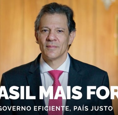 Fernando Haddad, de terno e gravata grená, em gabinete, com a Bandeira e o retrato de Lula ao fundo