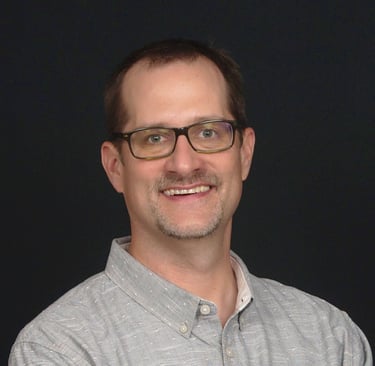 Jim Kalbach, a man with glasses and a gray shirt button up shirt 